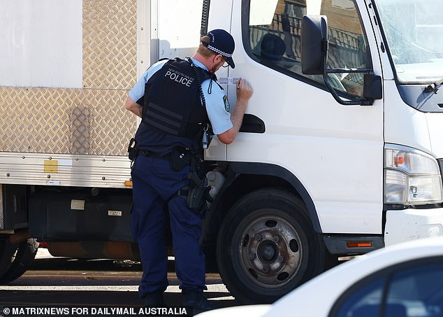 A photo of a police officer putting an evidence sticker on the door of a truck near his apartment on Monday